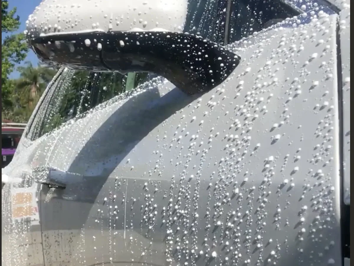 A protection topper beading across the door and mirror of a coated car during a maintenance visit