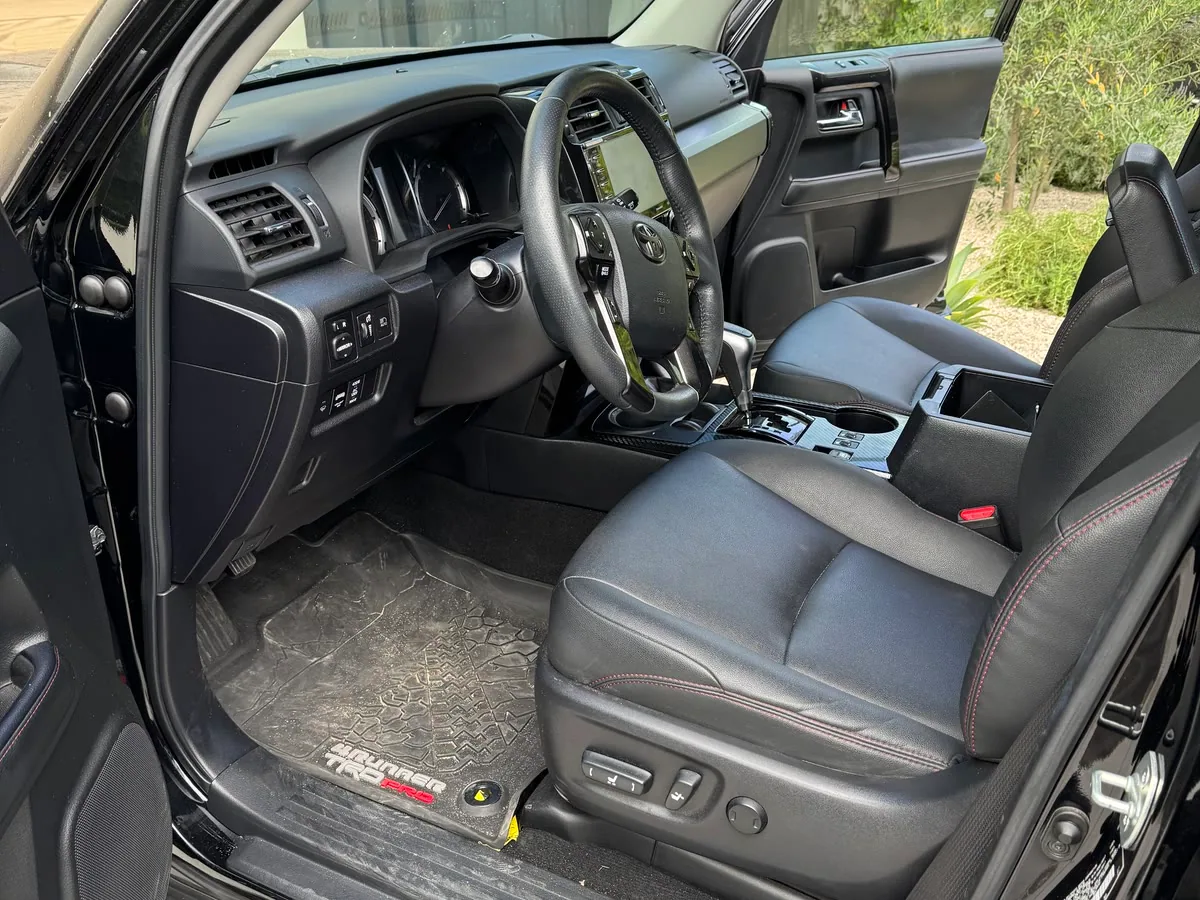 The driver's side of a clean SUV interior with the door open, leather seats, dash and console
