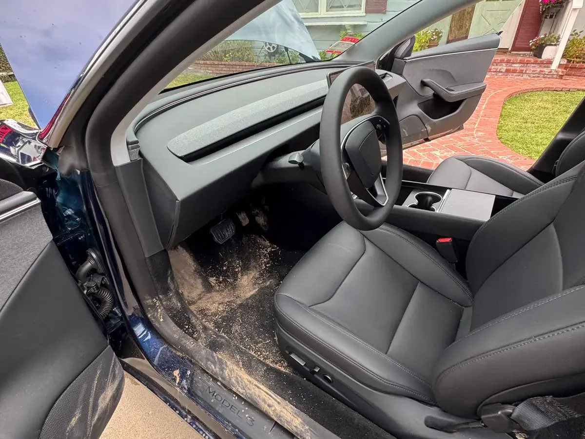 Dried mud caked into the door sill and carpet of a Tesla interior before extraction