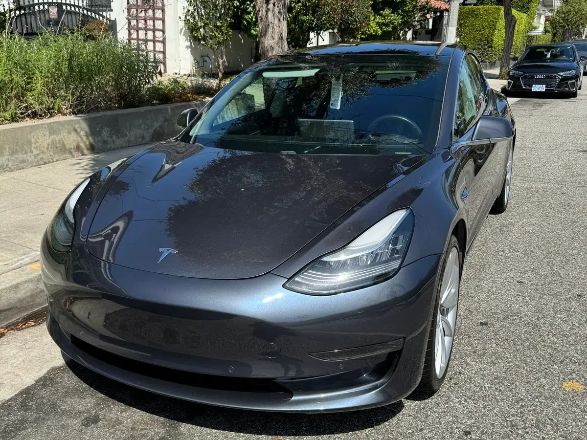 A dark grey Tesla Model 3 washed and dried at the kerb, one of the vehicles kept on a monthly plan