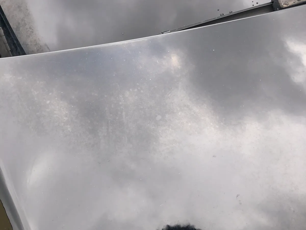 A hood where the clear coat has gone hazy and blotchy, the reflection breaking up instead of staying sharp