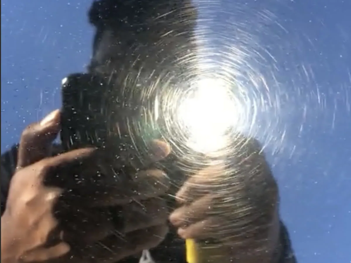 Swirl marks radiating around a light source on dark blue paint, the fine circular scratches an automatic wash leaves