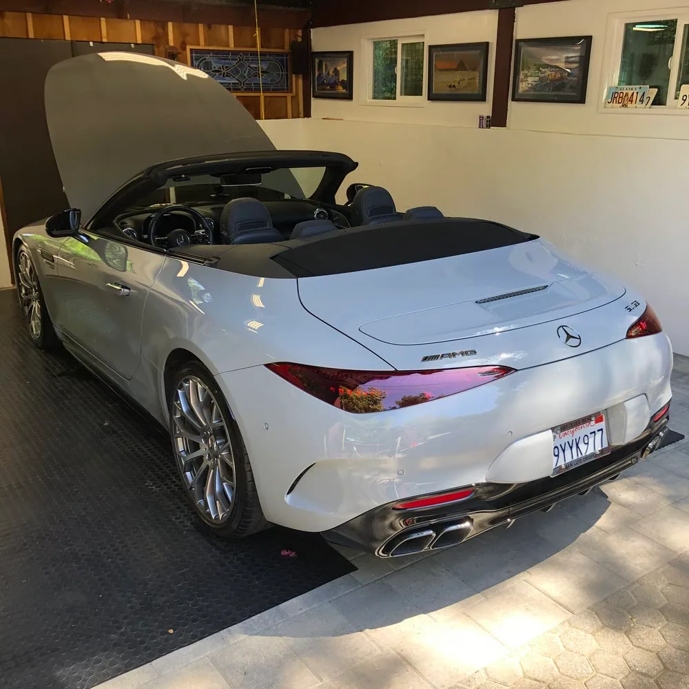 A white Mercedes-AMG SL 63 in a garage, roof down and the coated paint holding a clean reflection