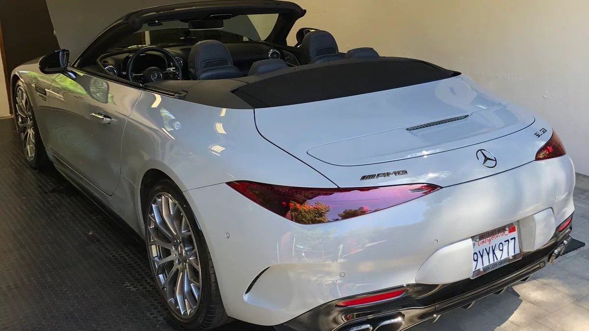 A white Mercedes-AMG SL 63 in a garage, the finished paint holding a clean reflection