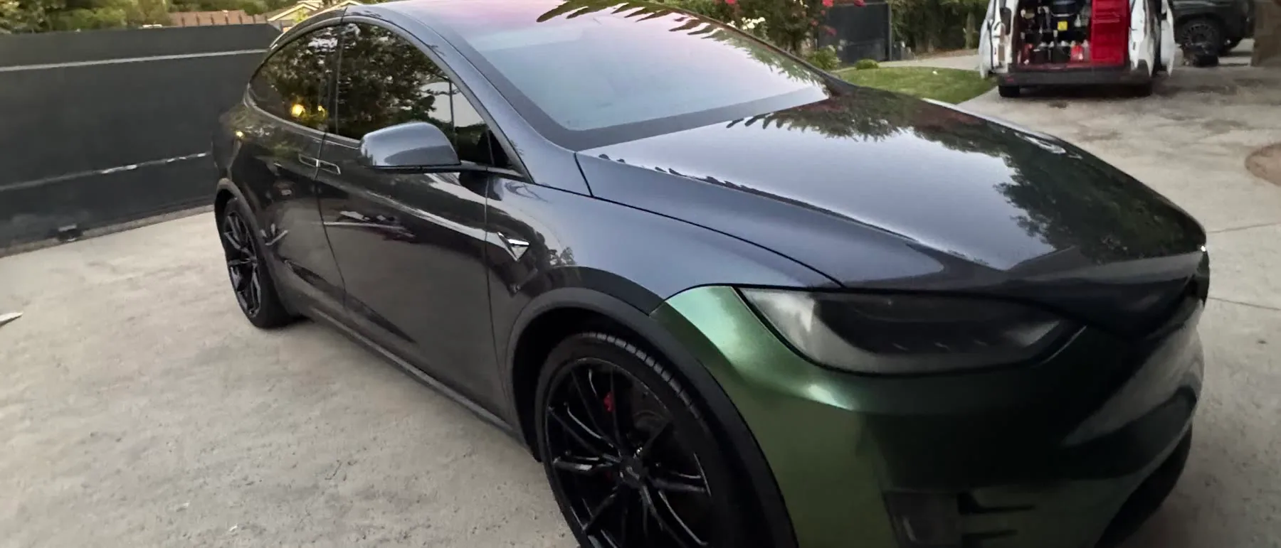 A dark green Tesla Model X detailed on a driveway with the TailorMade van open behind it, equipment racked and ready