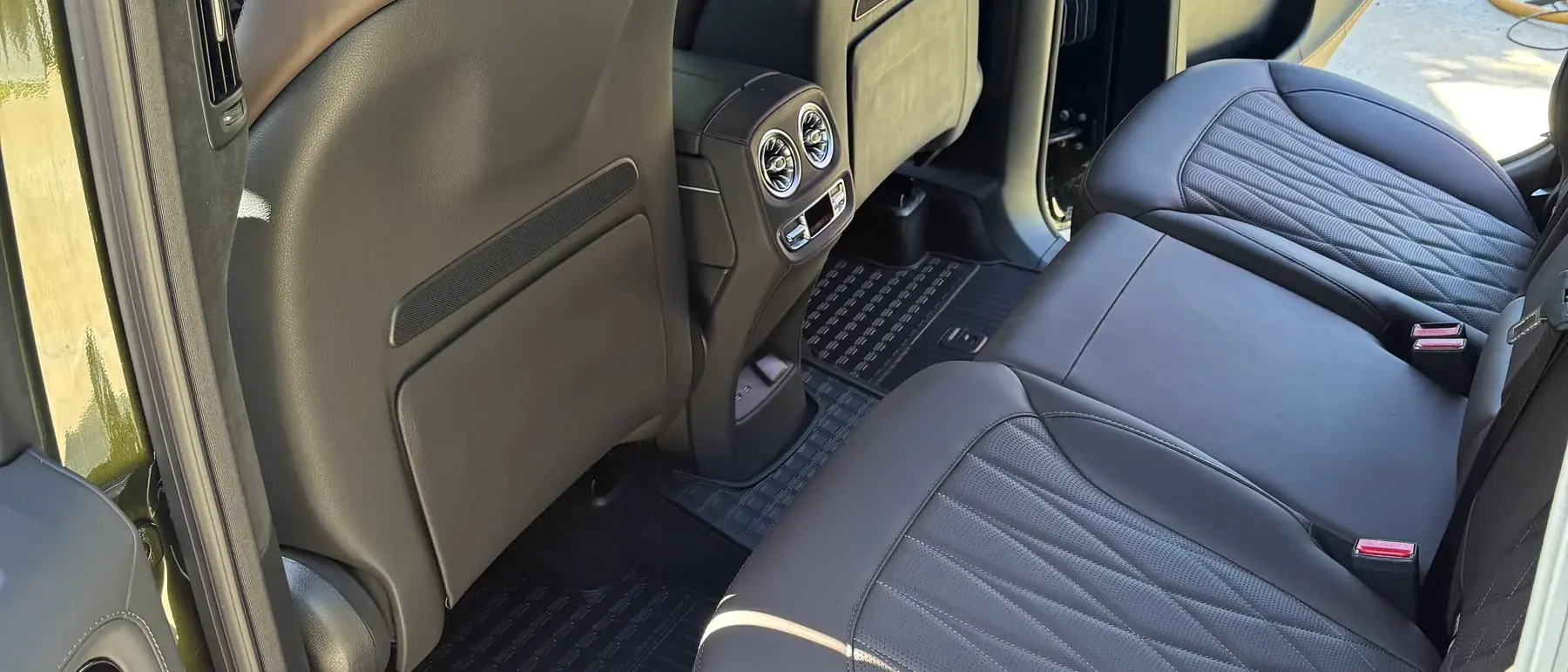 The rear seats, floor mats and center console of an SUV after an interior detail, leather clean and mats dressed